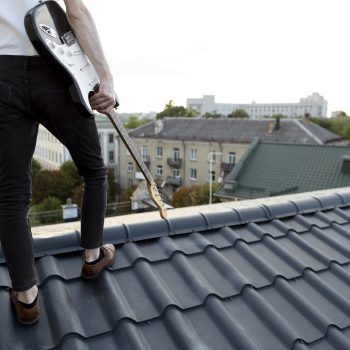 back-view-male-musician-roof-top-holding-electric-guitar